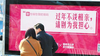 2月13日,兰州市客运中心门前,乘客从一“暖心”广告文案前走过。首席记者 裴强/摄