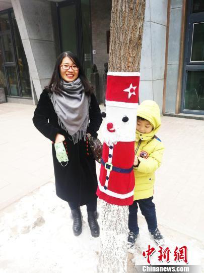 现场还吸引了一些年幼的孩童,他们在家长的帮助下,踮着脚尖给树木穿好了萌萌哒的新衣,并合影留念。 钟欣 摄