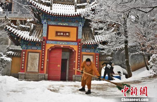 图为僧人扫去积雪。祁秋谨摄