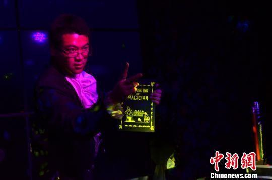 甘肃“90后”魔术师金林表演魔术:打开字典扉页,变出花朵。 崔琳 摄