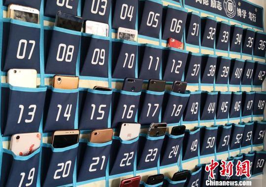 图为上课前,同学们陆续将手机放入手机袋。 刘玉桃 摄