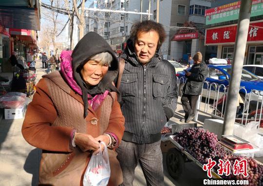 1月11日,张巨芳老人患上感冒,当地爱心人士陪老人买感冒药。 甘芬 摄