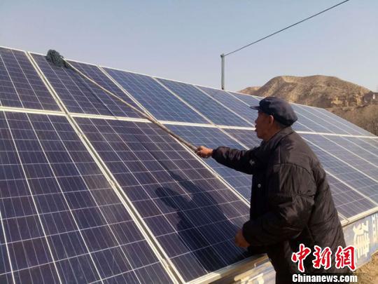 2月5日,兰州市皋兰县石洞镇豆家庄村村民王玉灿正在擦拭光太阳电池板。 闫姣 摄
