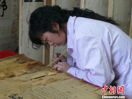 黄静从事档案修复工作,如今已有13个年头了,经她“医治”而“复活”的档案已“堆积如山”。图为黄静在“手术台”上修复档案。 钟欣 摄