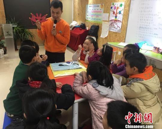 1月27日,兰州市白银路街道社区服务中心聚集众多学生学习情商课。老师在课堂上展示已经做好的面具,激发学生好奇心,大家发散思维一起讨论制作面具的步骤。 张婧 摄