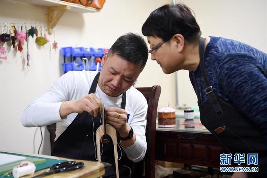 李丽(右)在工作室指导顾客制作皮具(1月12日摄)。 新华社记者 范培珅 摄