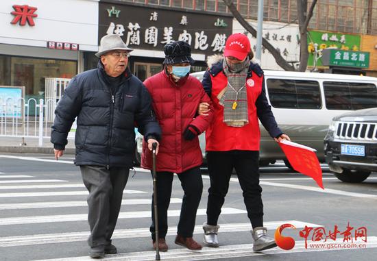 志愿服务队队员帮助老人过马路