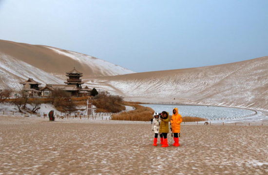 2020年12月8日,游客在敦煌市鸣沙山月牙泉景区欣赏雪景。