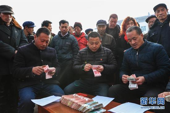 1月20日,在元古堆村2019年度企业带动入股分红大会上,村干部在清点分红款,准备发给村民。