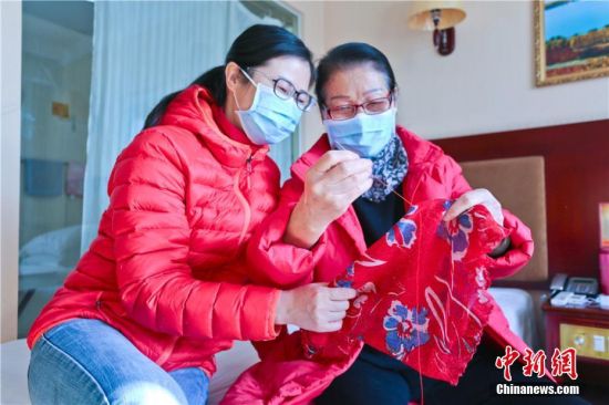 图为在湖北籍游客在丝巾绣上“平安、大爱、幸福”,准备离开时送给张掖人。