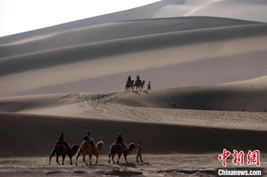 图为游人乘骆驼体验大漠风光。
