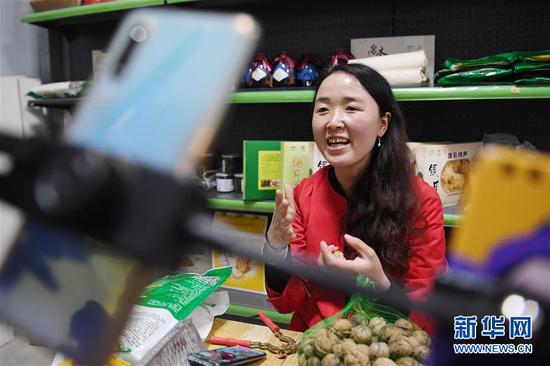 梁倩娟在自己的电商服务点利用网络直播平台展示家乡农产品(3月8日摄)。新华社记者 陈斌 摄