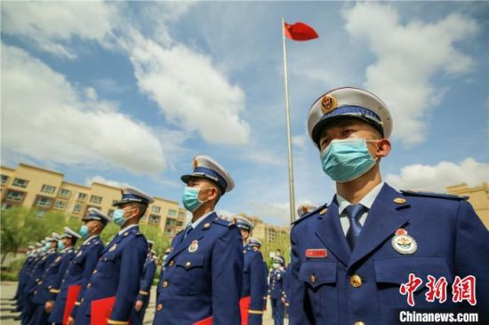 图为佩戴消防救援衔的新消防员在国旗下整齐列队。 张小军 摄