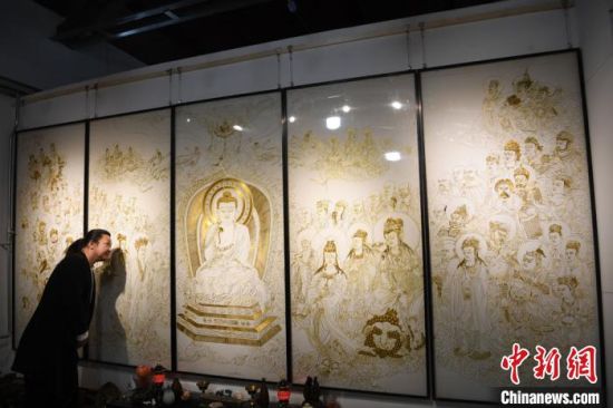 5月中旬,甘肃省民间艺人李海明珐琅艺术馆在兰州创意文化产业园落成揭牌,他多年来创作的40多幅作品在艺术馆集中展出。图为李海明介绍自己用3000多米金丝、历时3年创作出的《说法图》掐丝画。