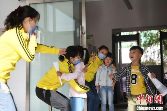 图为幼儿复课,与老师拥抱。