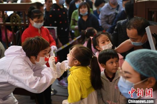 图为幼儿接受校医检查。