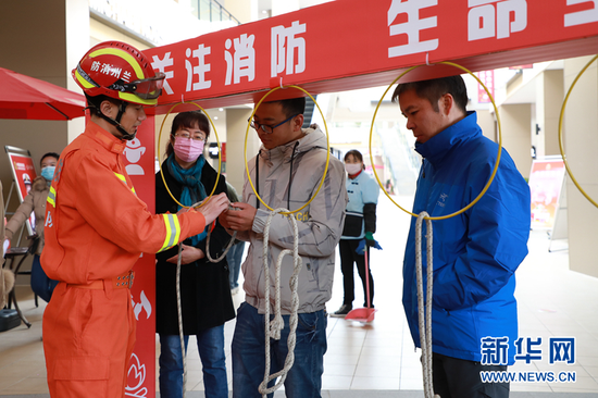 图为消防队员向市民介绍安全绳索。新华网发(童张伟 摄)