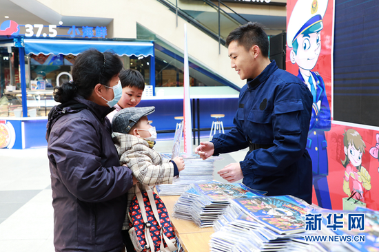 图为消防队员给市民现场赠阅《漫画消防》云图册。新华网发(刘欣瑜 摄)