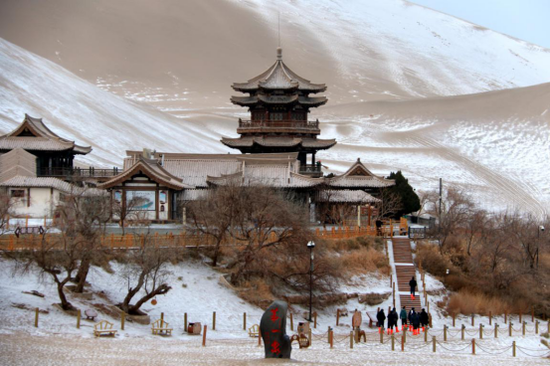 2020年12月8日,游客在敦煌市鸣沙山月牙泉景区欣赏雪景(无人机照片)。