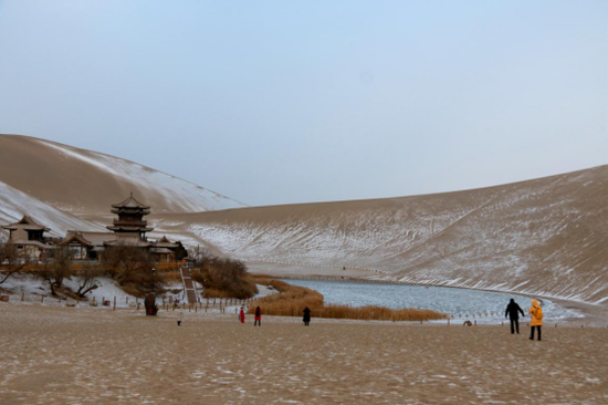 2020年12月8日,游客在敦煌市鸣沙山月牙泉景区欣赏雪景。