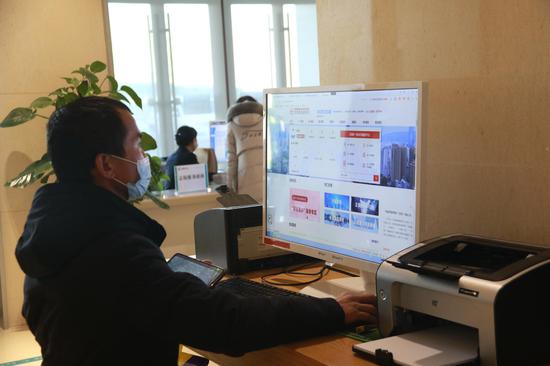 2020年12月22日,办事群众在敦煌市民中心使用自助电脑办理业务。