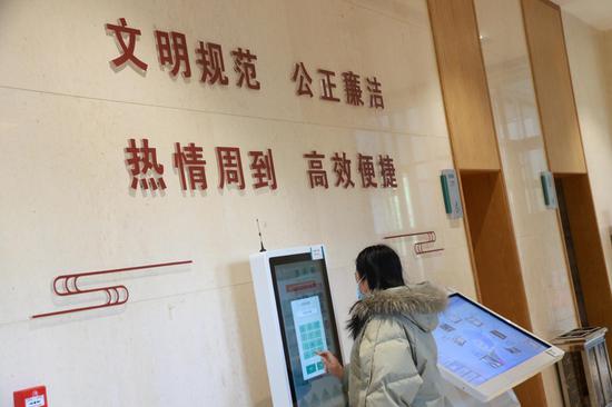 2020年12月22日,办事群众在敦煌市民中心使用智能取号机取号。