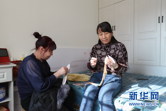 在甘肃省白银市会宁县钟鼓楼安置小区,王兴瑞(右)在家里和朋友绣鞋垫。新华社记者 马希平 摄