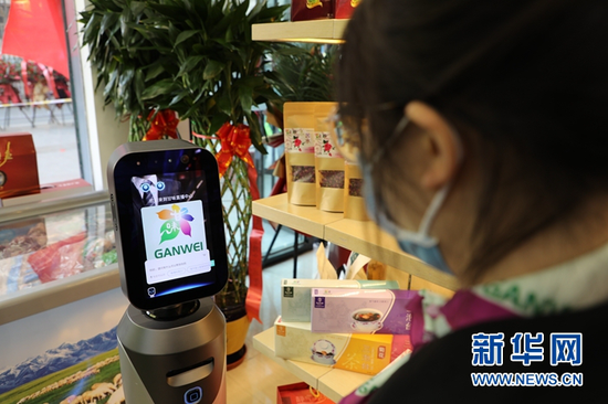 顾客和“甘味”农产品展销直播中心内的机器人交流。新华网(王生元 摄)