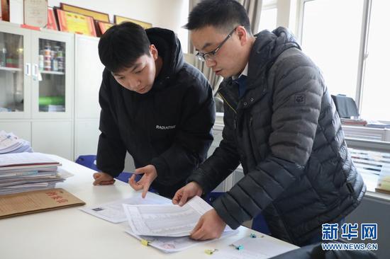在甘肃农业大学教师办公室,苌烁森(左)帮老师整理资料(1月22日摄)。新华社记者 马希平 摄