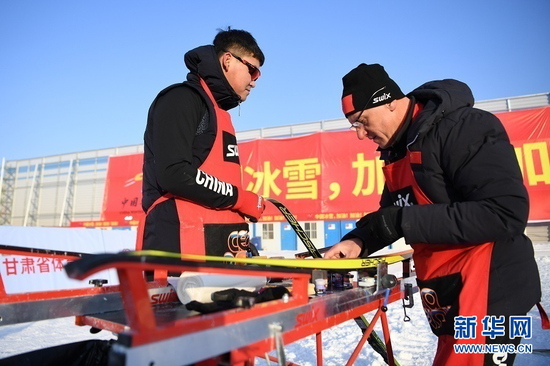 1月23日,打蜡师王一涵(左)和泰利尔在检查运动员的雪板。 新华社记者 陈斌 摄