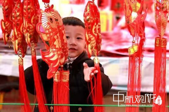 白天,各式各样的干货、一幅幅的对联、诱人的糖果、高挂的大红灯笼,吸引民众排队购买