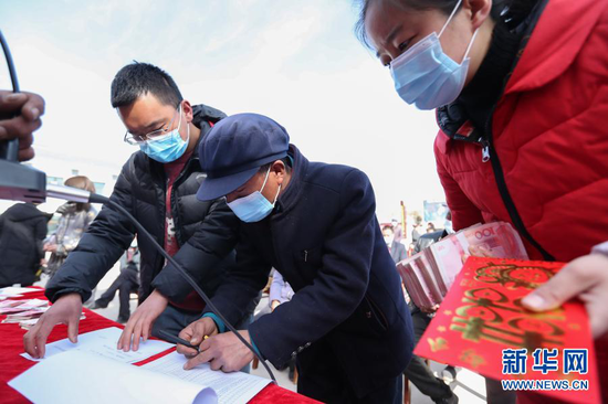 2月5日,在元古堆村文化广场,村民曾玉成(中)领取分红款。新华社记者 马希平 摄