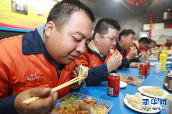 2月11日,在金川集团三矿区采矿二工区井下食堂,工人们一起吃年夜饭。新华社记者 杜哲宇 摄