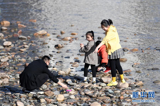 2月18日,市民带着孩子在黄河兰州段河床上捡石头。新华社记者 范培珅 摄