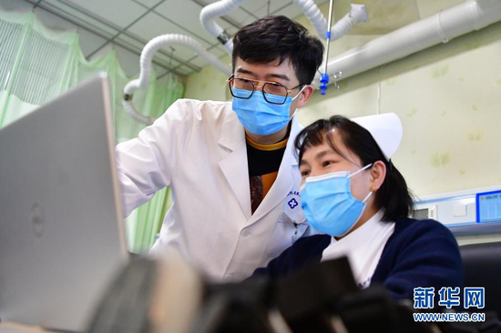 柳伟(左)和同事交流治疗方案(1月11日摄)。新华社记者 陈斌 摄