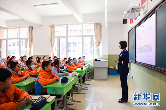 图为宣传人员给学生讲解消防安全知识。新华网发(张家纶 摄)