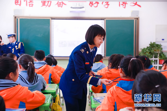图为宣传人员给学生发放铅笔、笔袋等消防主题纪念品。新华网发(张家纶 摄)