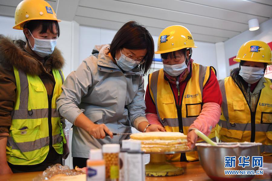 杜萱(左二)和女工友一起在工地上制作蛋糕庆祝“三八”妇女节(3月4日摄)。新华社记者 陈斌 摄