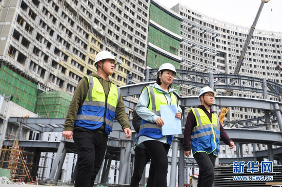 杜萱(中)带领技术人员从甘肃省妇女儿童医疗综合体项目三标段工地上走过(3月4日摄)。新华社记者 陈斌 摄