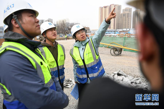 杜萱(右一)带领技术人员在甘肃省妇女儿童医疗综合体项目三标段工地上查看施工进度(3月4日摄)。新华社记者 陈斌 摄