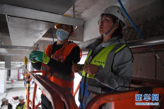 杜萱(右)在甘肃省妇女儿童医疗综合体项目三标段工地上检查指导工人作业(3月4日摄)。新华社记者 陈斌 摄