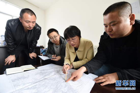 3月11日,在平凉市崆峒区林业技术工作站,张文玉(右二)和同事查看植树造林区域地形图。新华社记者 范培珅 摄