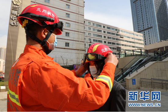 图为消防员给市民试戴消防帽。新华网发(刘欣瑜 摄)