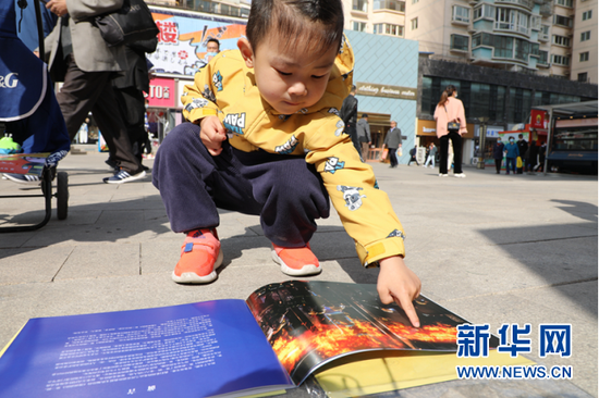 图为小朋友在活动现场阅读《漫画消防》宣传册。新华网发(刘欣瑜 摄)