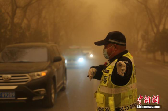 3月15日,甘肃多地遭遇沙尘天气,一名交警戴口罩执勤。 胡广信 摄
