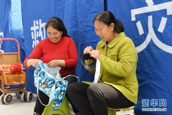 3月16日,在舟曲县果耶镇磨里村、果耶村滑坡灾害应急避险临时安置点,受灾群众在帐篷外做针线。新华社记者 范培珅 摄