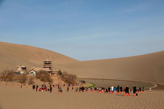 2021年4月10日,游客在甘肃省敦煌市鸣沙山月牙泉景区游览。