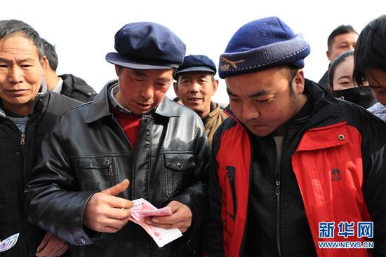 1月20日,在元古堆村2019年度企业带动入股分红大会上,村民在清点领到的分红。