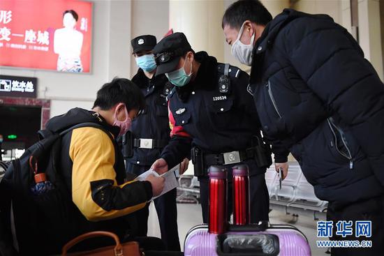 2月10日,兰州车站派出所民警铁勇智(右二)在兰州火车站候车大厅向旅客宣传防疫知识。