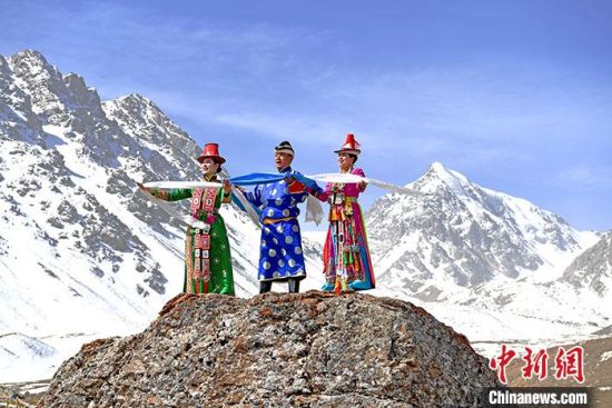 图为4月中旬,裕固族民众身着民族服装在巴尔斯雪山下。